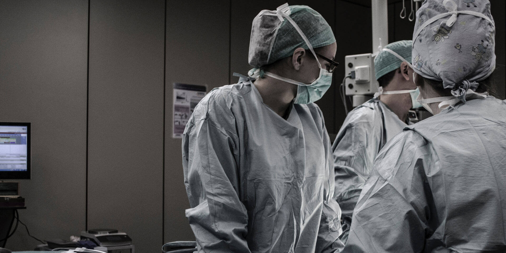 Two doctors in surgical masks and gowns stand next to each other.