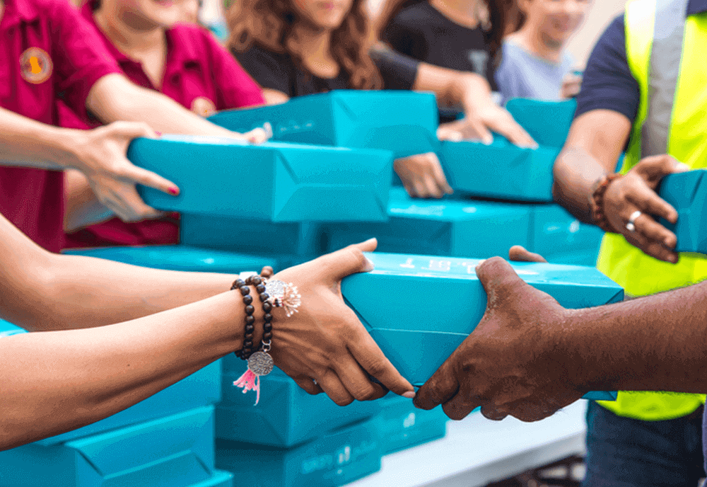 A group of people holding boxes and shaking hands.